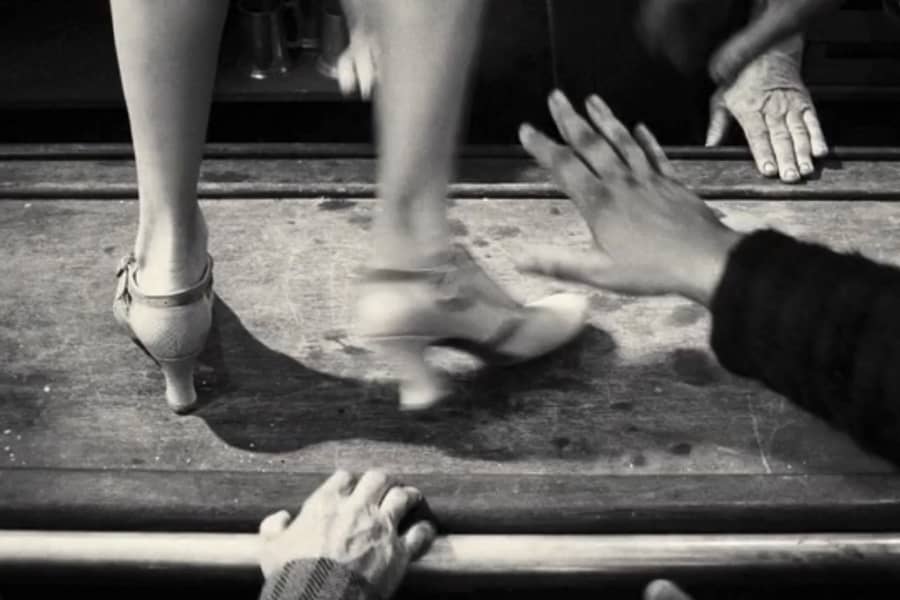 feet dancing on a bar surrounded by men’s hands