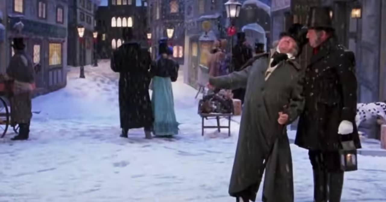 Scrooge stands in a snowy city street